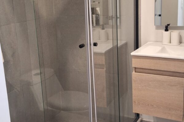 Stylish bathroom with a glass-enclosed shower, floating wooden vanity, and neutral-toned tiles for a modern look.