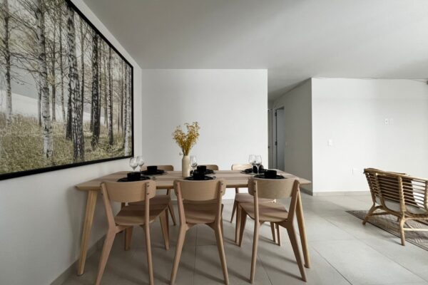 Bright dining space featuring a sleek table setting with black dishware, yellow floral decor, and a clean, contemporary design.