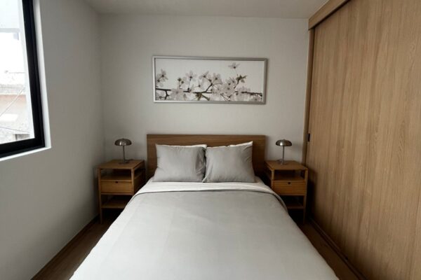 Bright bedroom with a clean design, white bedspread, and wooden furnishings for a cozy feel.