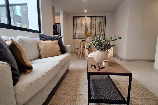 Stylish living area featuring a beige sofa, decorative plants, and a wooden table with modern accents.